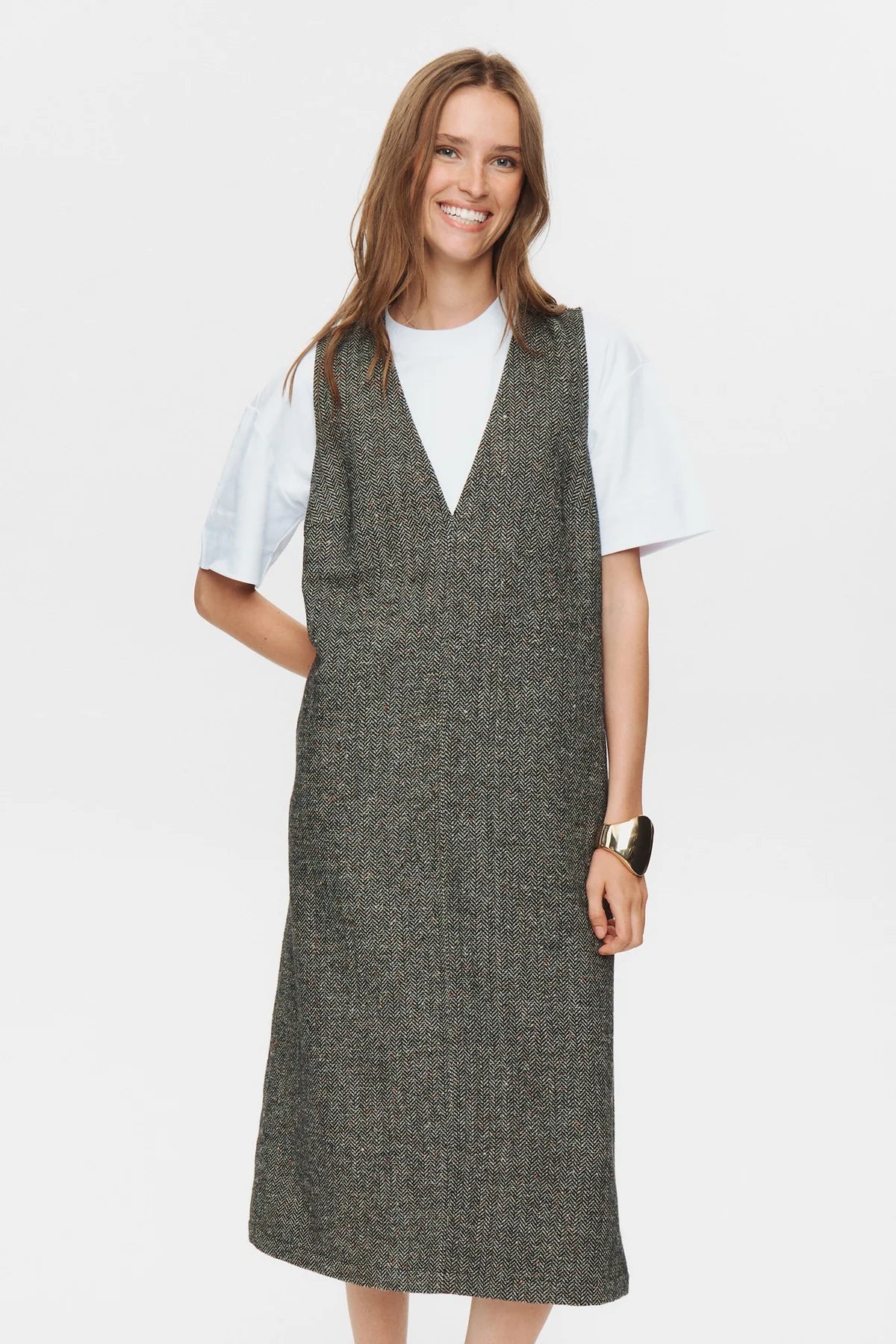 Woman wearing a gray dress over a white shirt on a white background