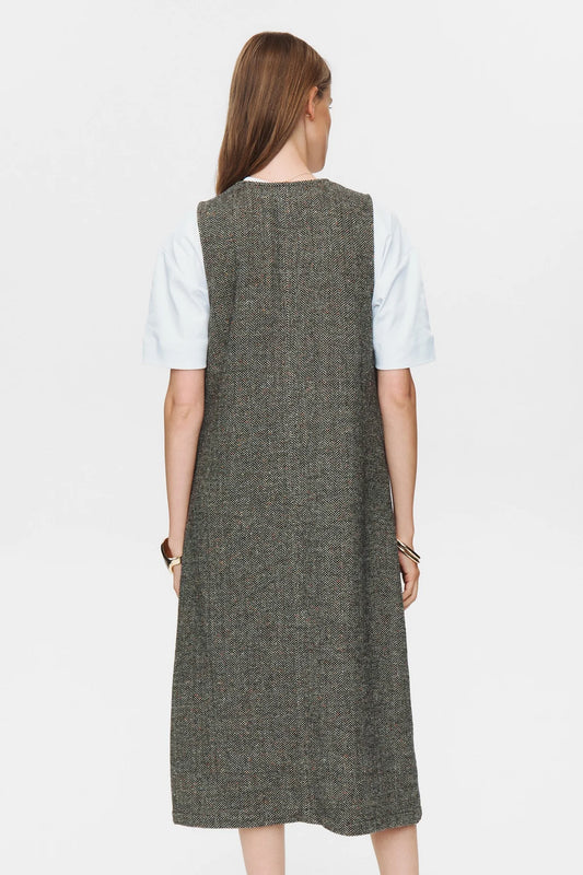 Woman wearing a long gray dress over a white shirt on a white background