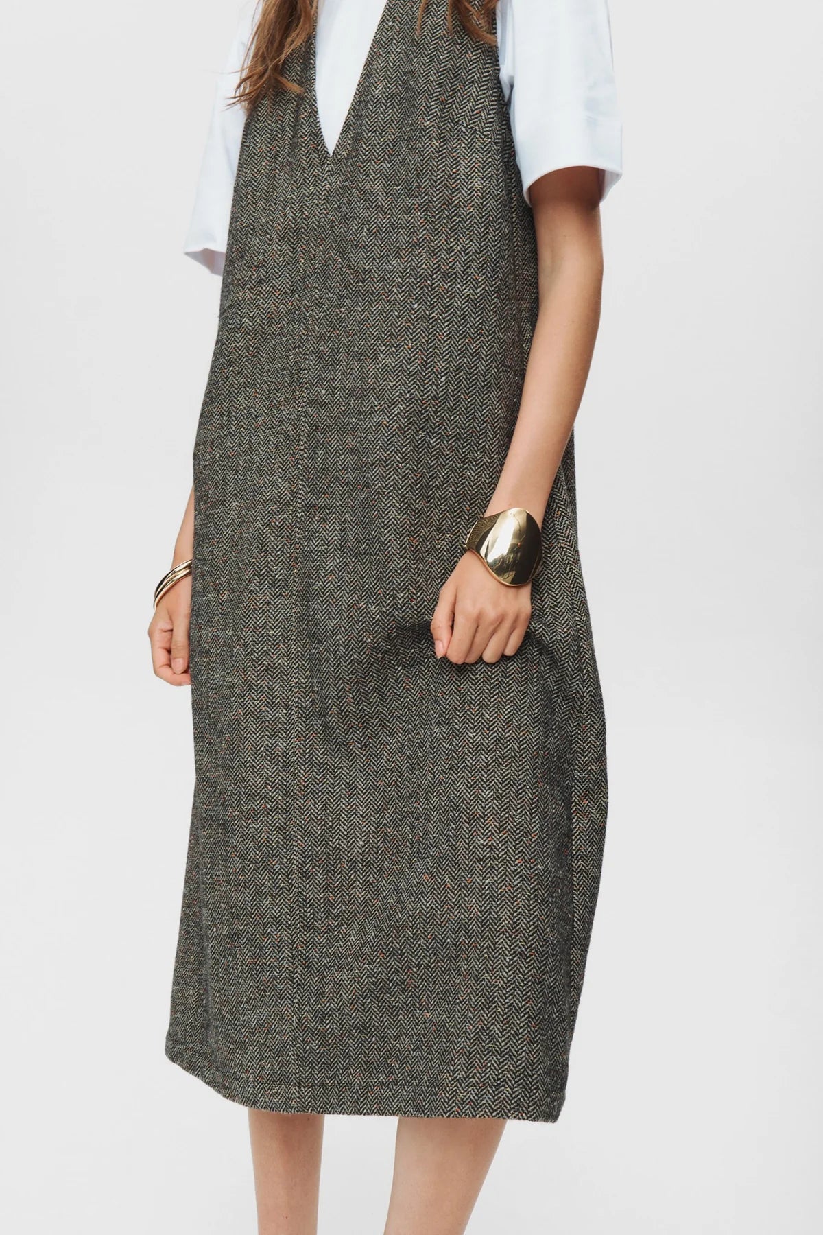 Person wearing a gray dress over a white shirt on a plain background