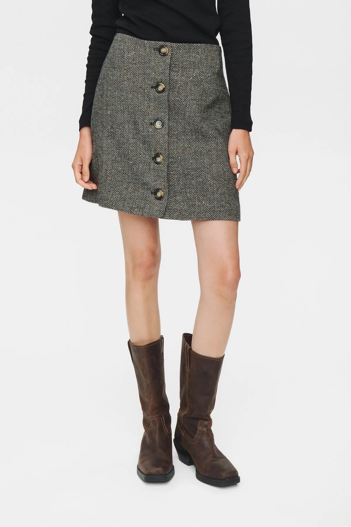 Person wearing a gray button-up skirt with a plain background