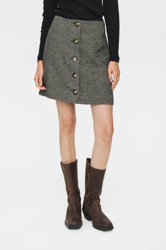 Person wearing a gray button-up skirt with a plain background
