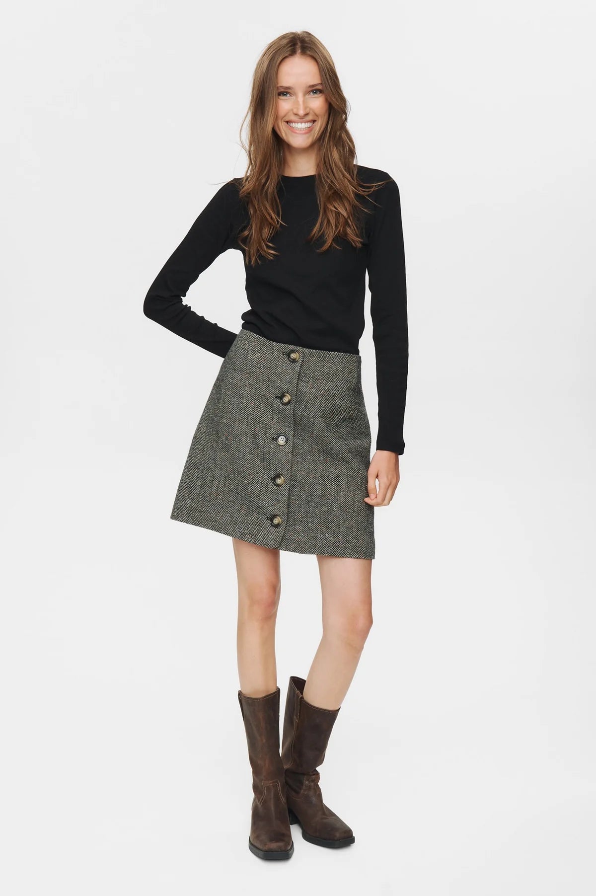 Woman wearing a black sweater and gray skirt with buttons on a white background