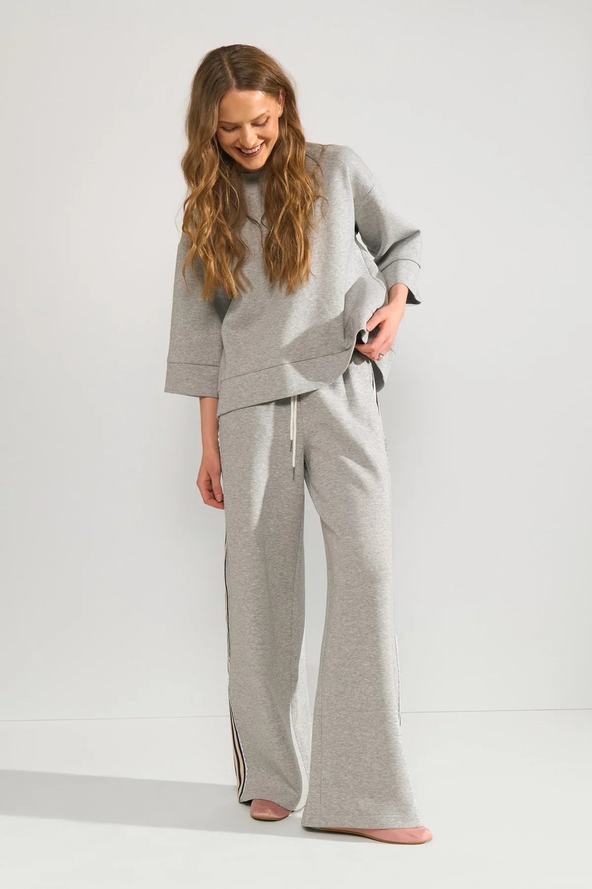 Woman wearing a gray outfit with wide-leg pants on a white background