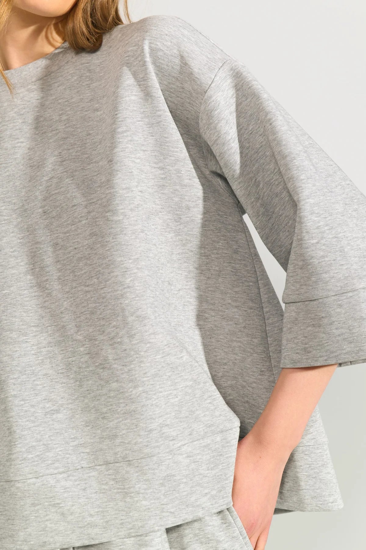 Gray oversized t-shirt worn by a person on a light gray background