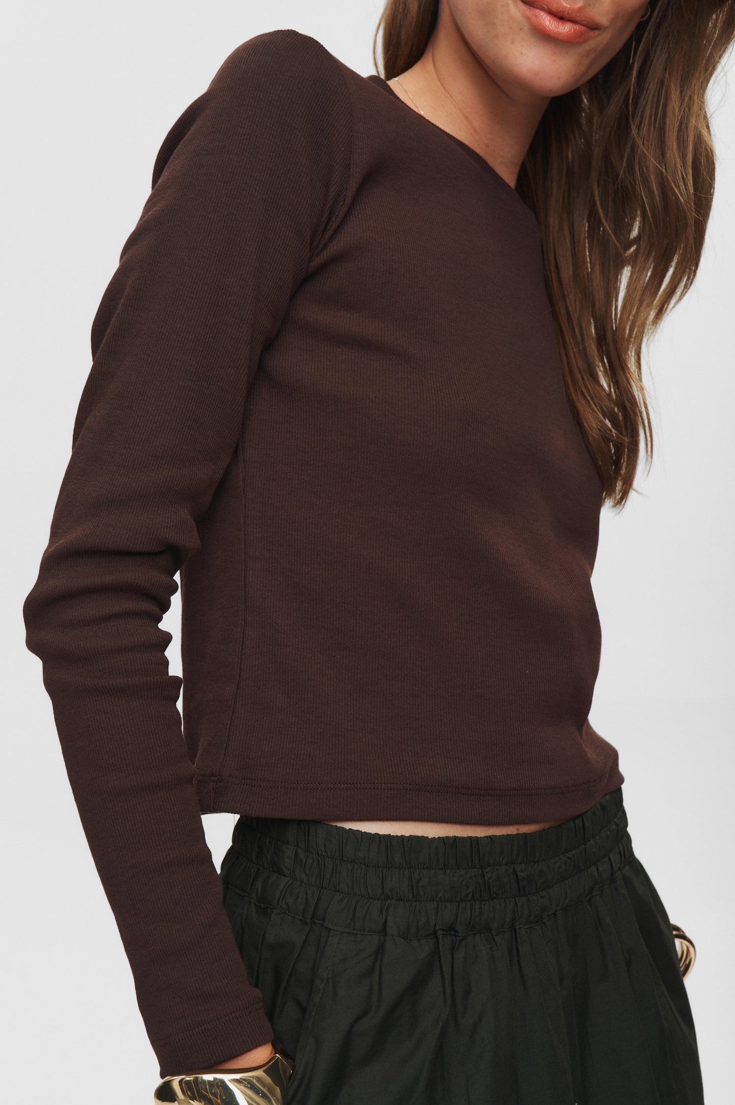 Brown long-sleeve top worn by a person on a white background