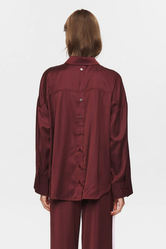 Person wearing a burgundy satin outfit on a white background