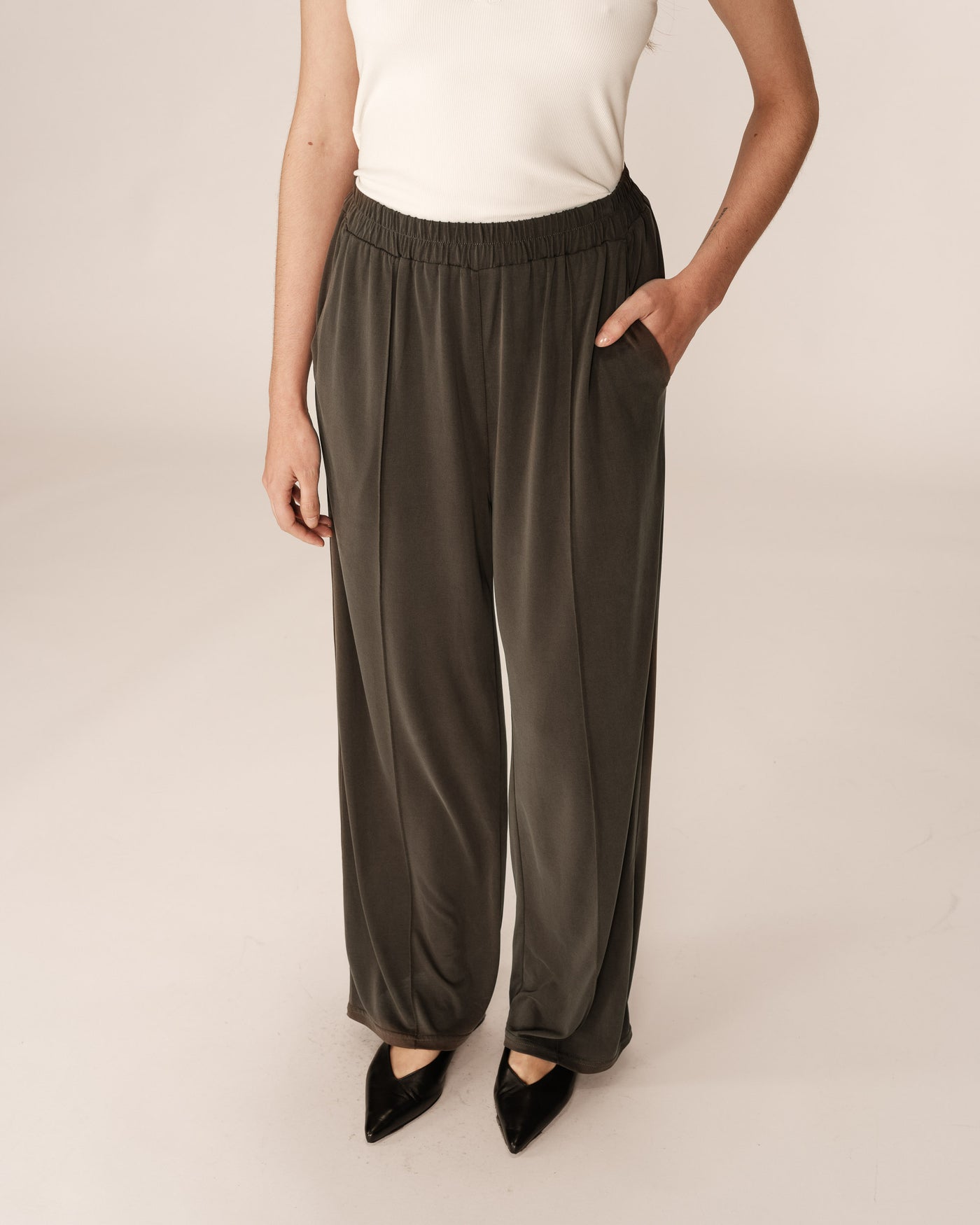 Person wearing dark green wide-leg pants on a plain background