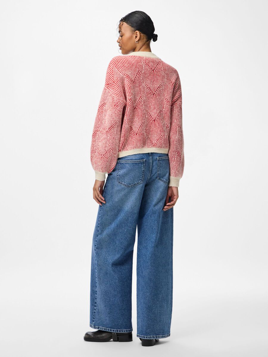 Person wearing a red patterned sweater and blue jeans on a white background