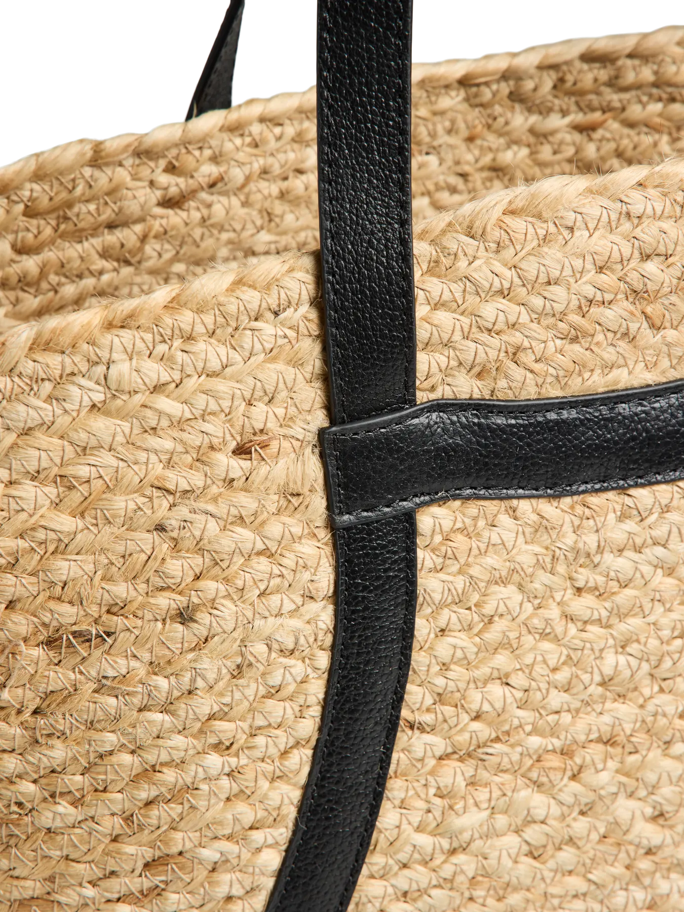 Close-up of a straw bag with a black strap on a white background