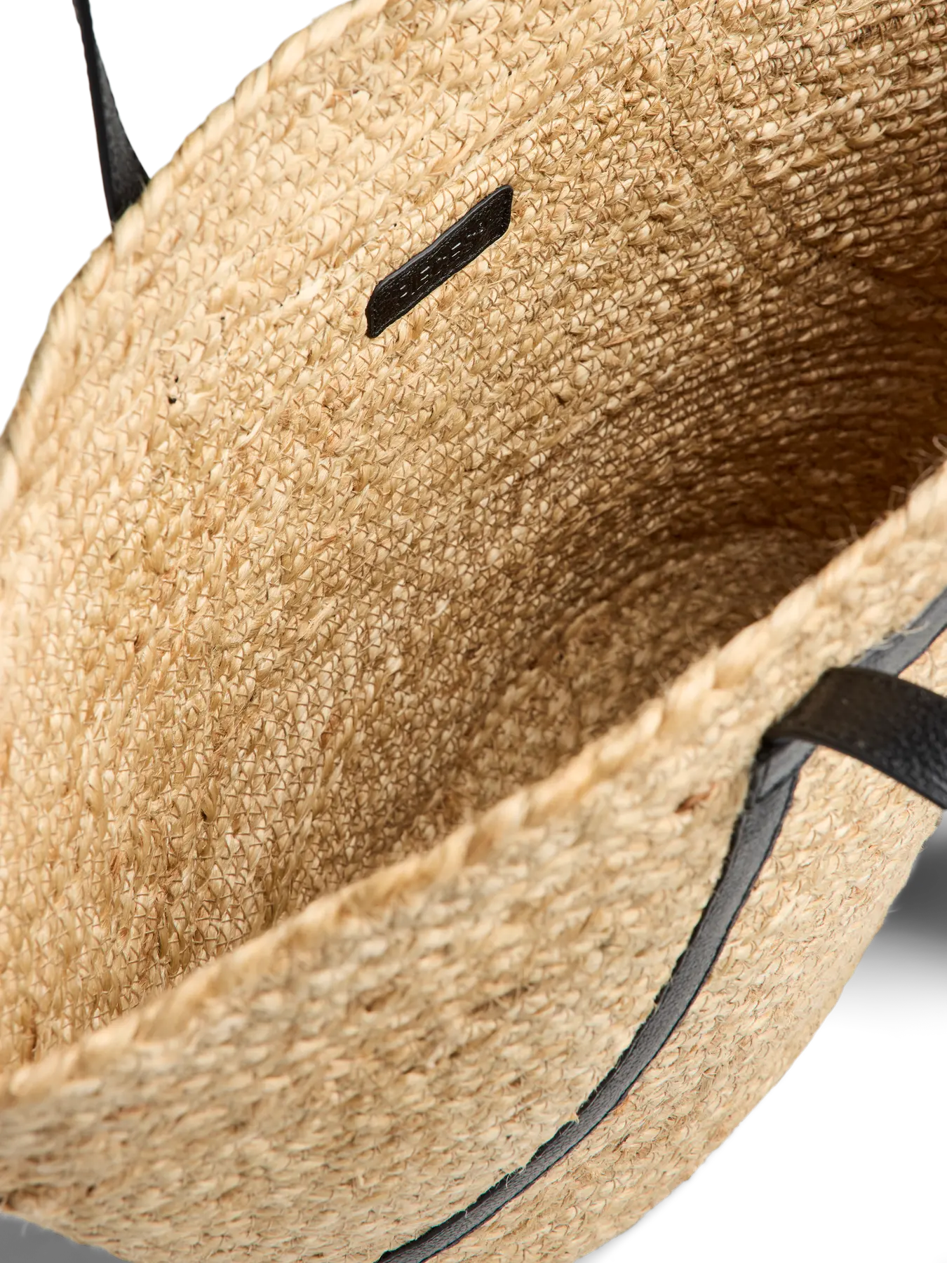 Close-up of a textured beige sandal with black straps on a white background