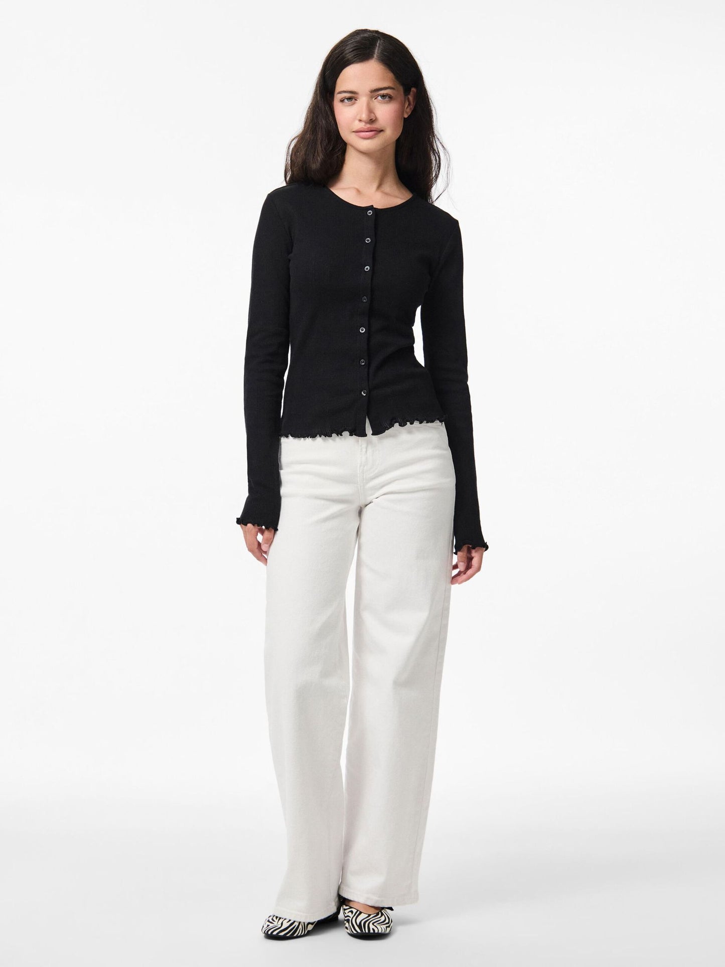 Woman wearing a black cardigan and white pants on a white background