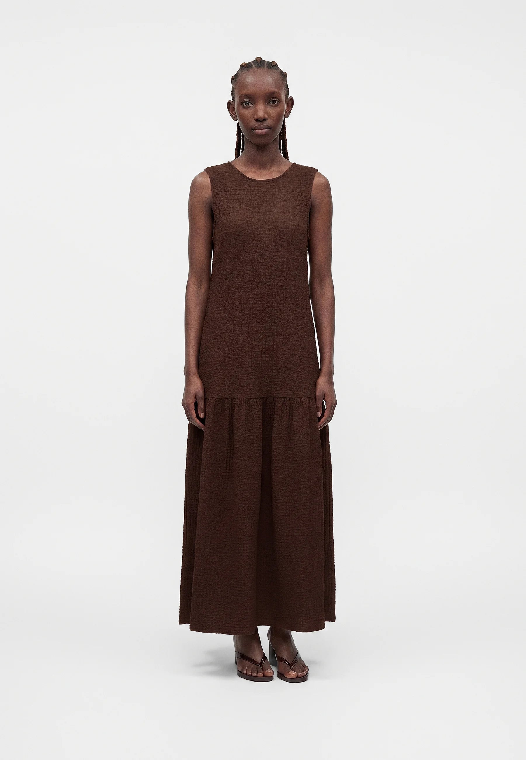 Person wearing a brown dress with a plain white background