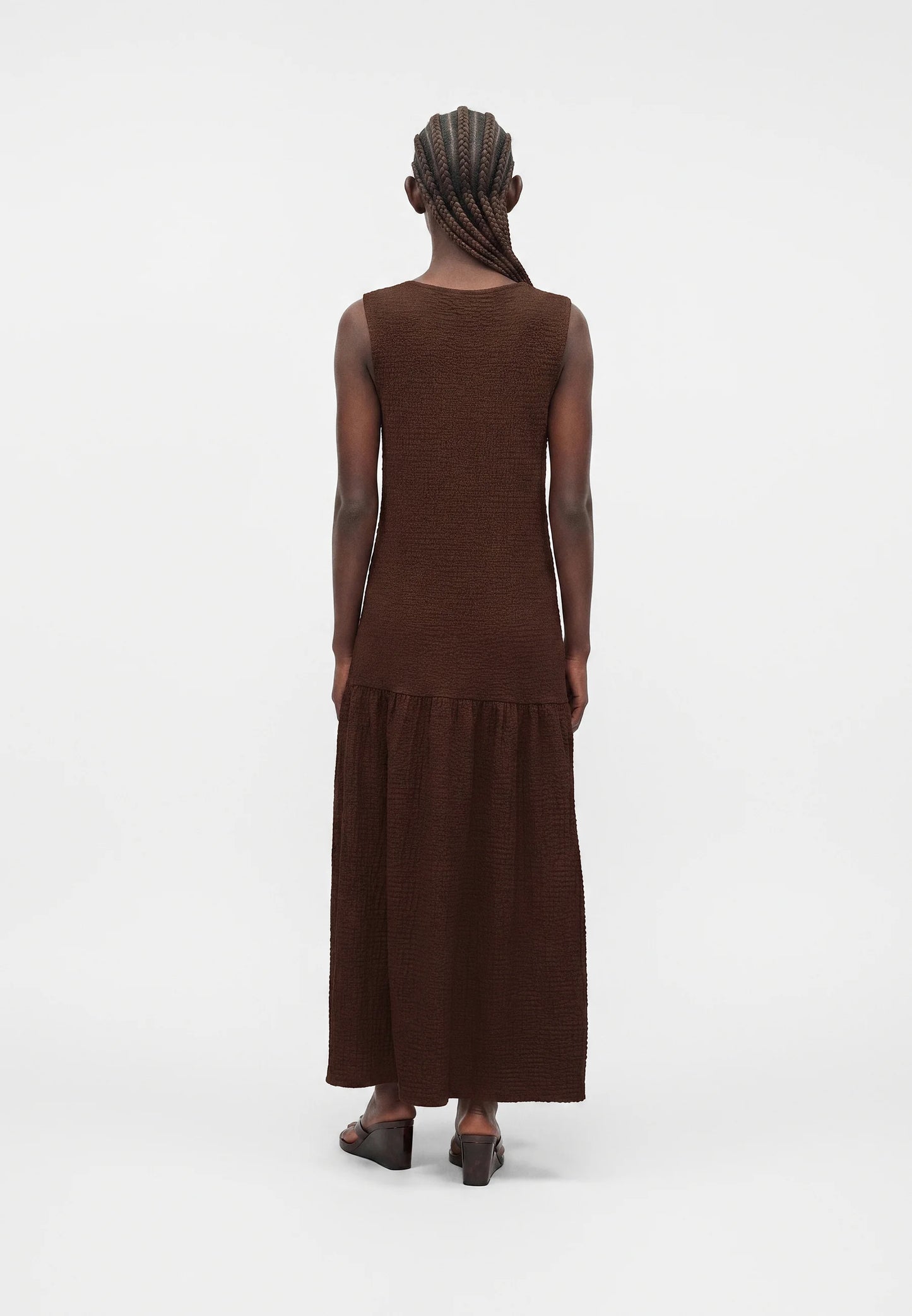 Person wearing a brown dress with a plain white background