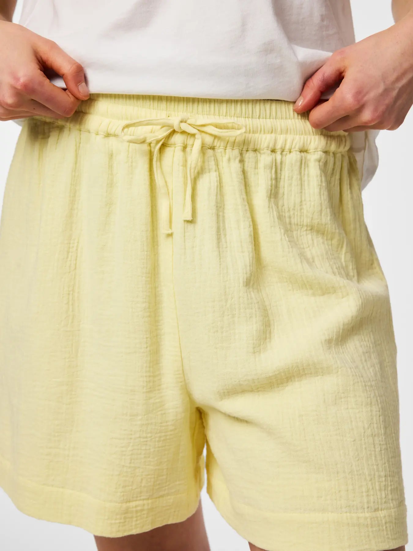 Yellow shorts with a drawstring on a plain background