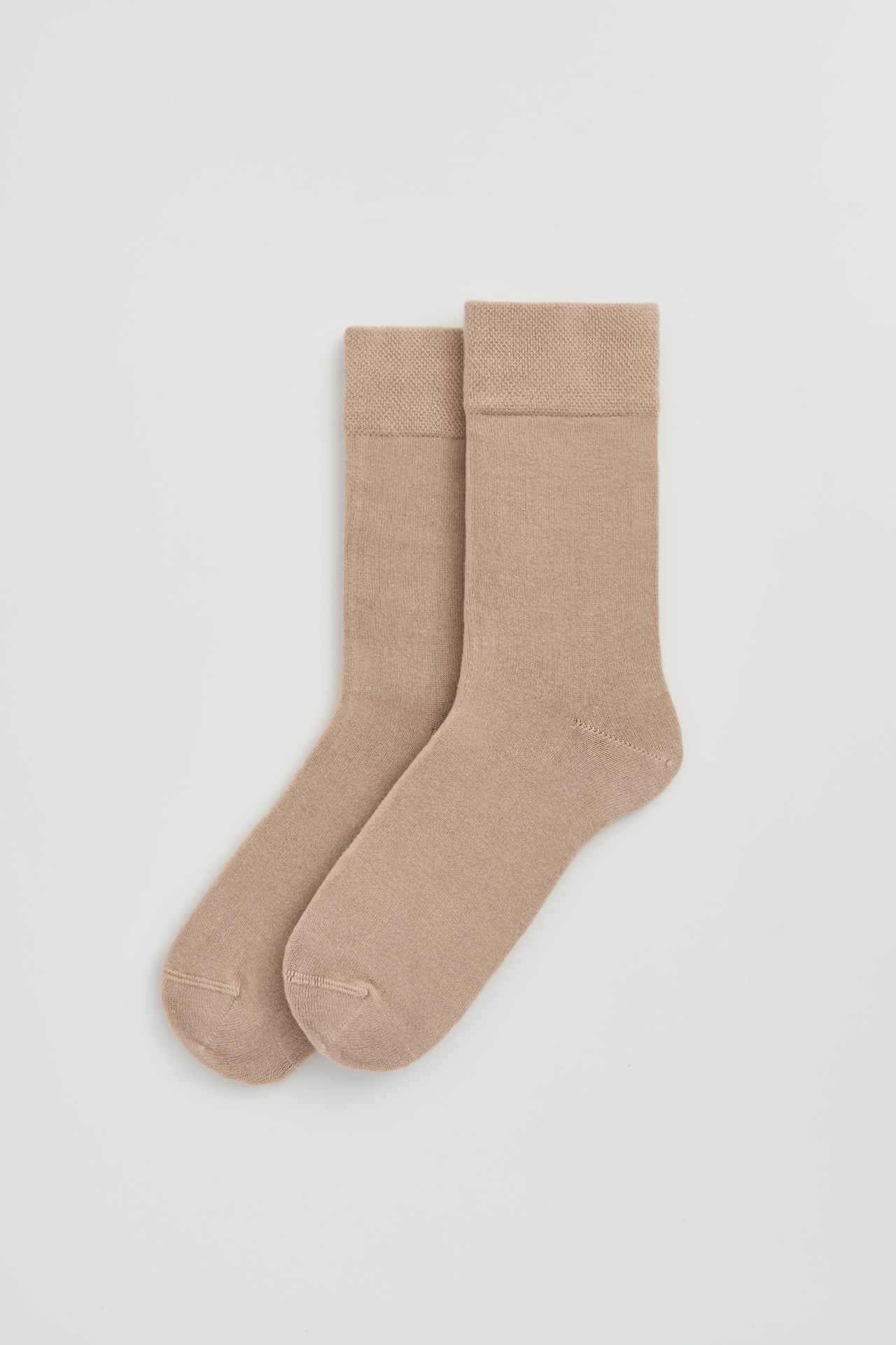 Pair of beige socks on a light gray background