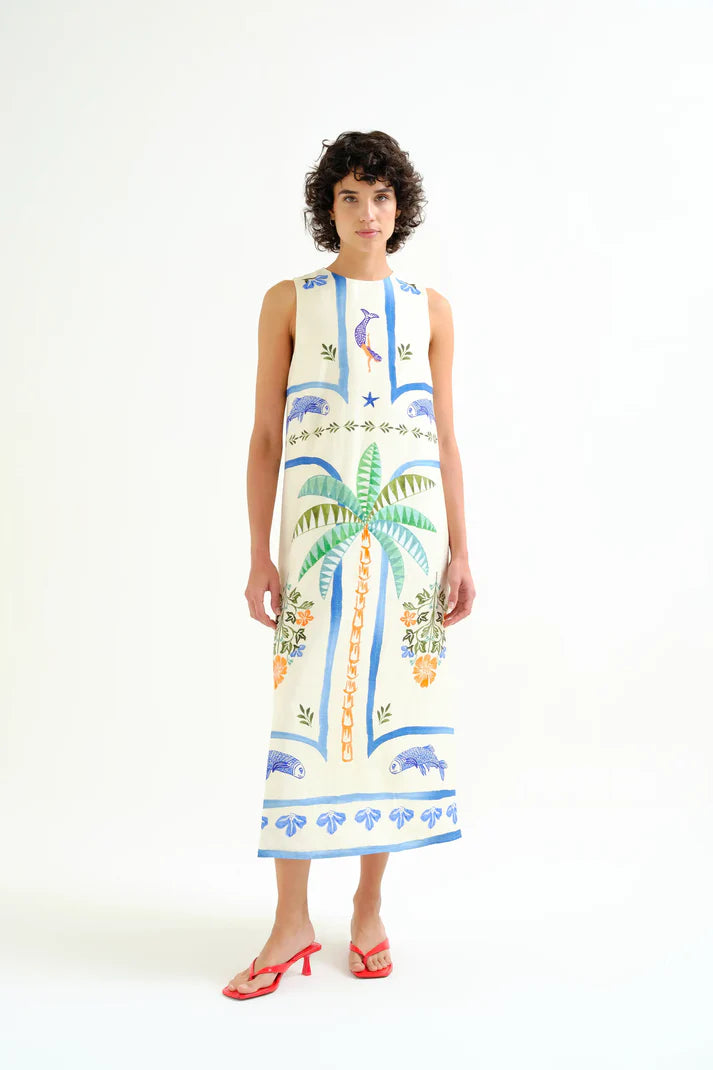 Woman wearing a sleeveless dress with tropical patterns on a white background