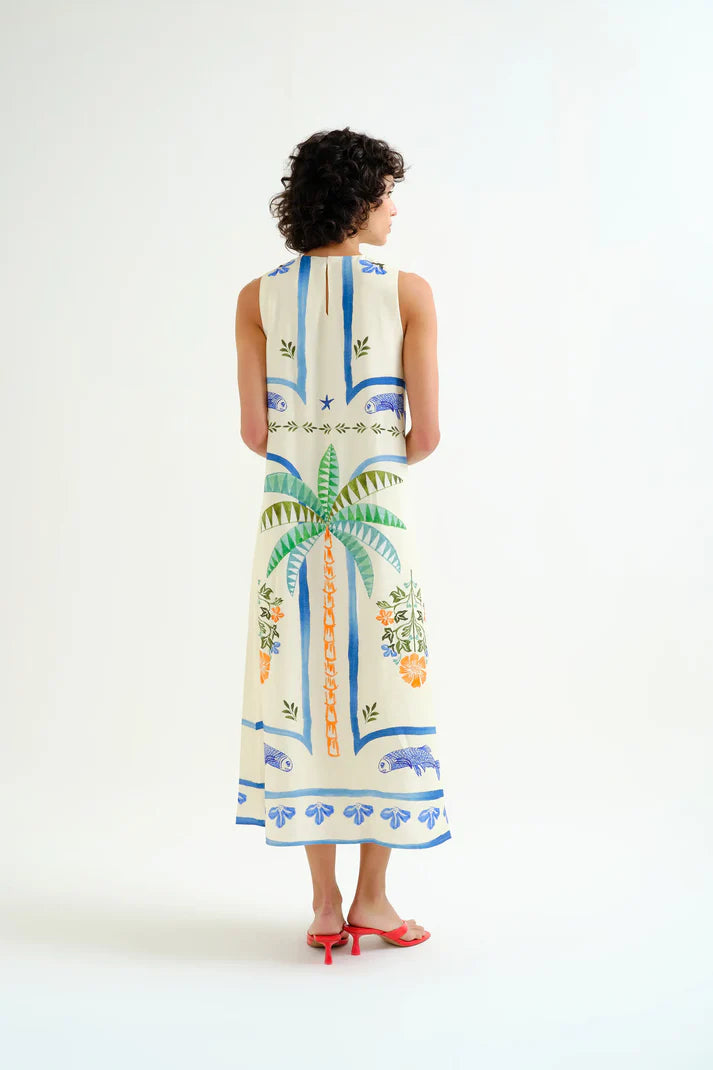Woman wearing a sleeveless dress with tropical patterns on a white background