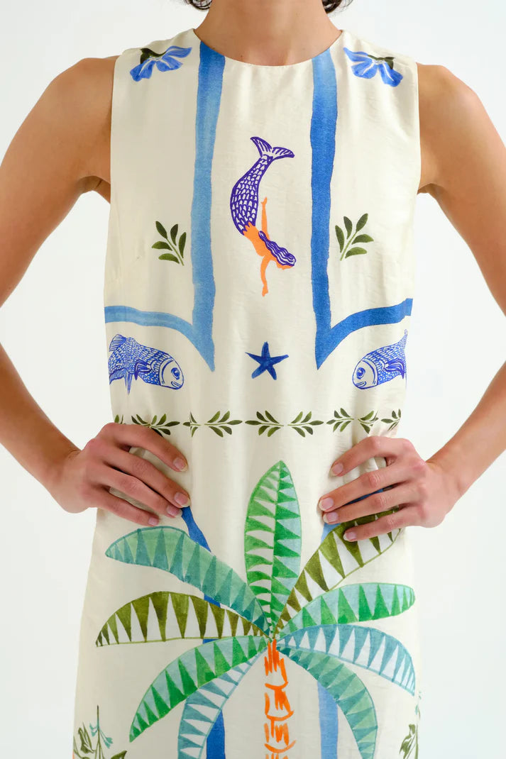 Woman wearing a sleeveless dress with tropical patterns on a white background