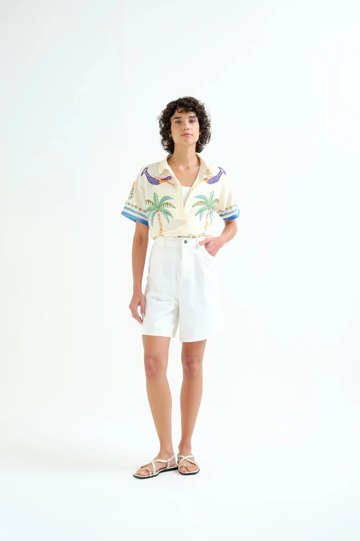 Person wearing a patterned shirt and white shorts on a white background