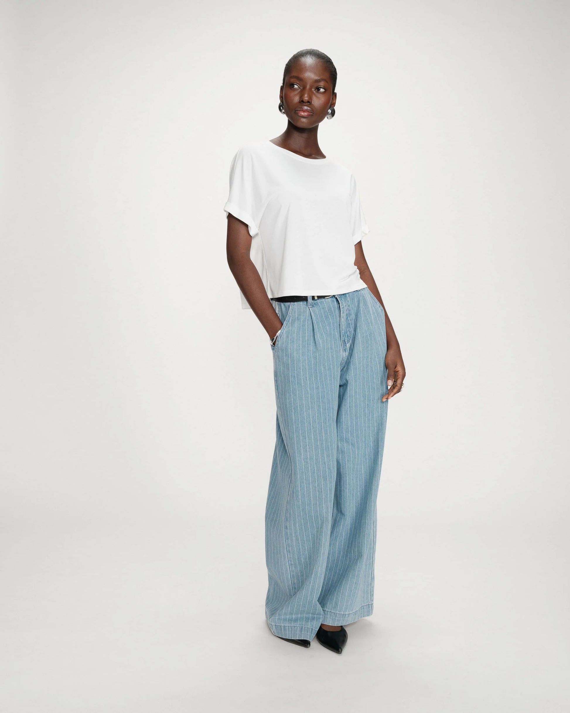 Person wearing a white top and blue striped pants on a white background