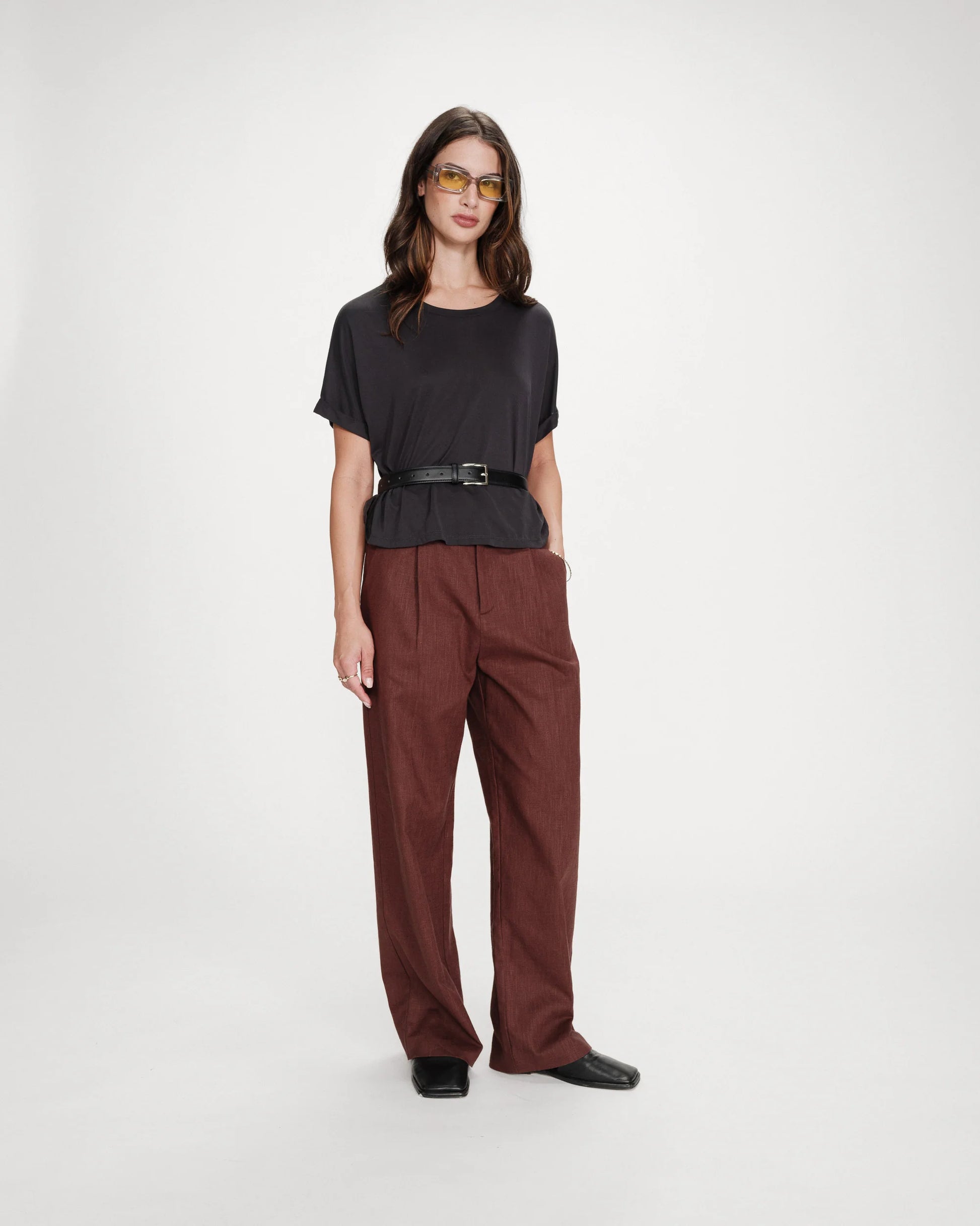 Woman wearing a black top and brown pants on a white background
