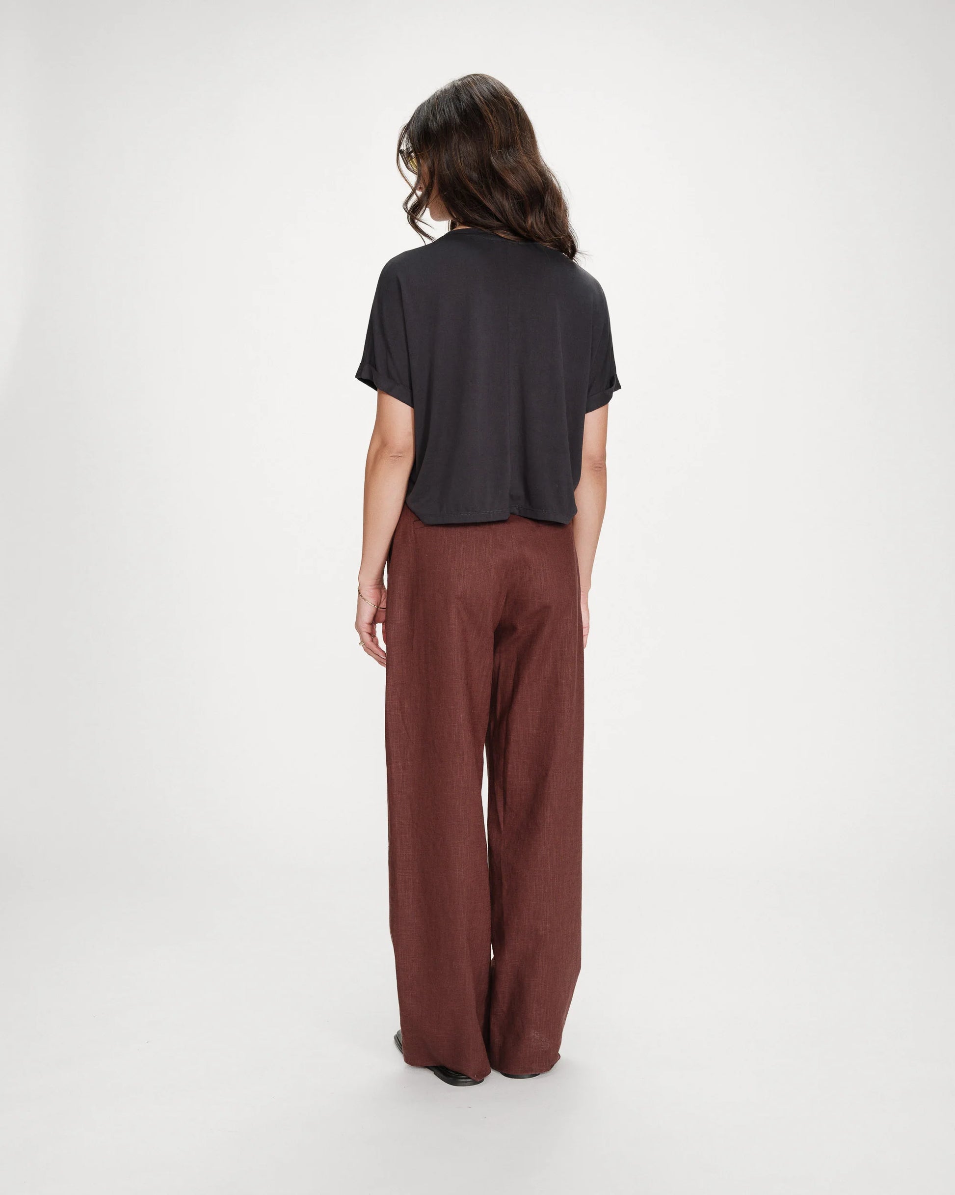 Person wearing a black top and brown pants on a white background
