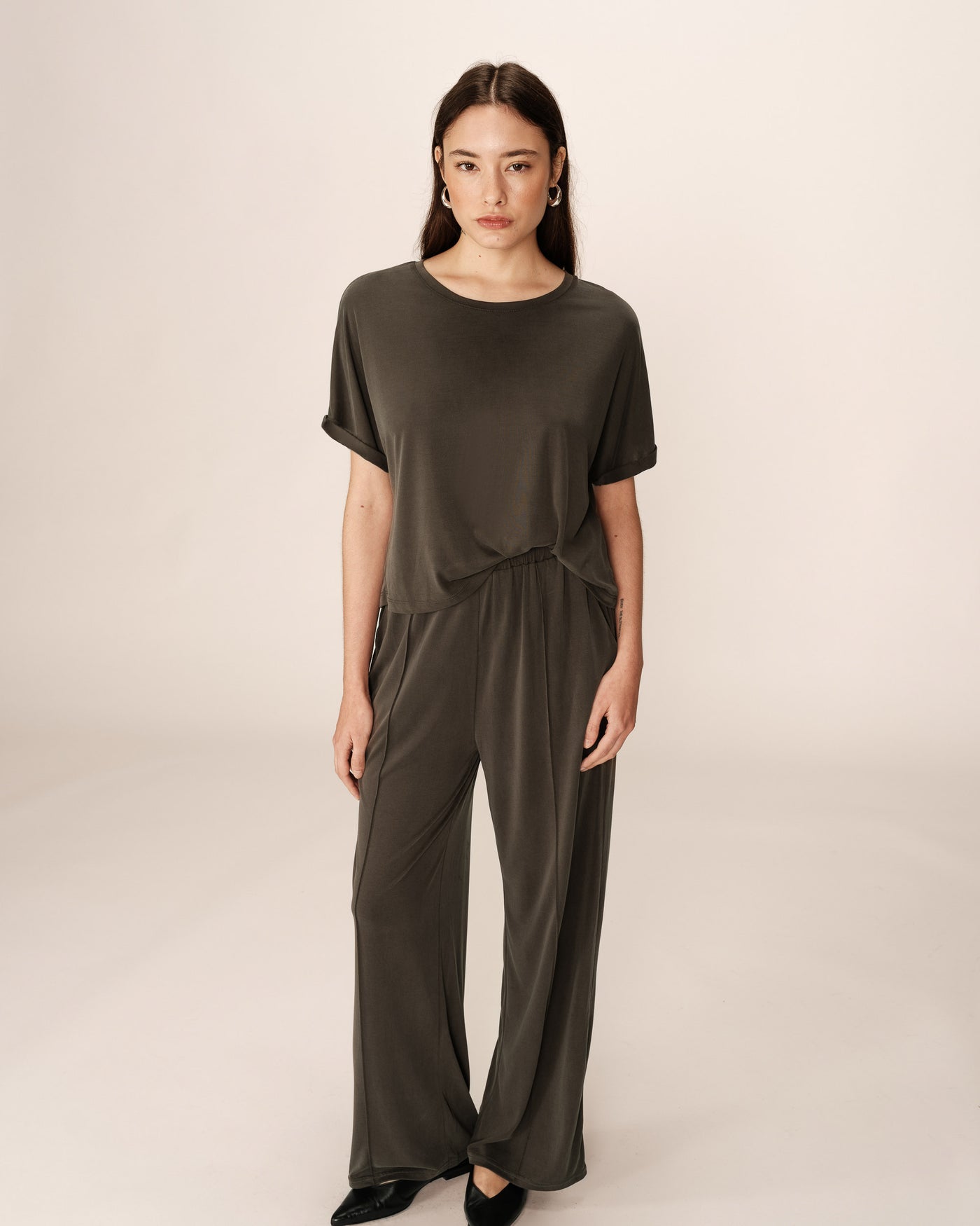 Woman wearing a dark green outfit on a beige background