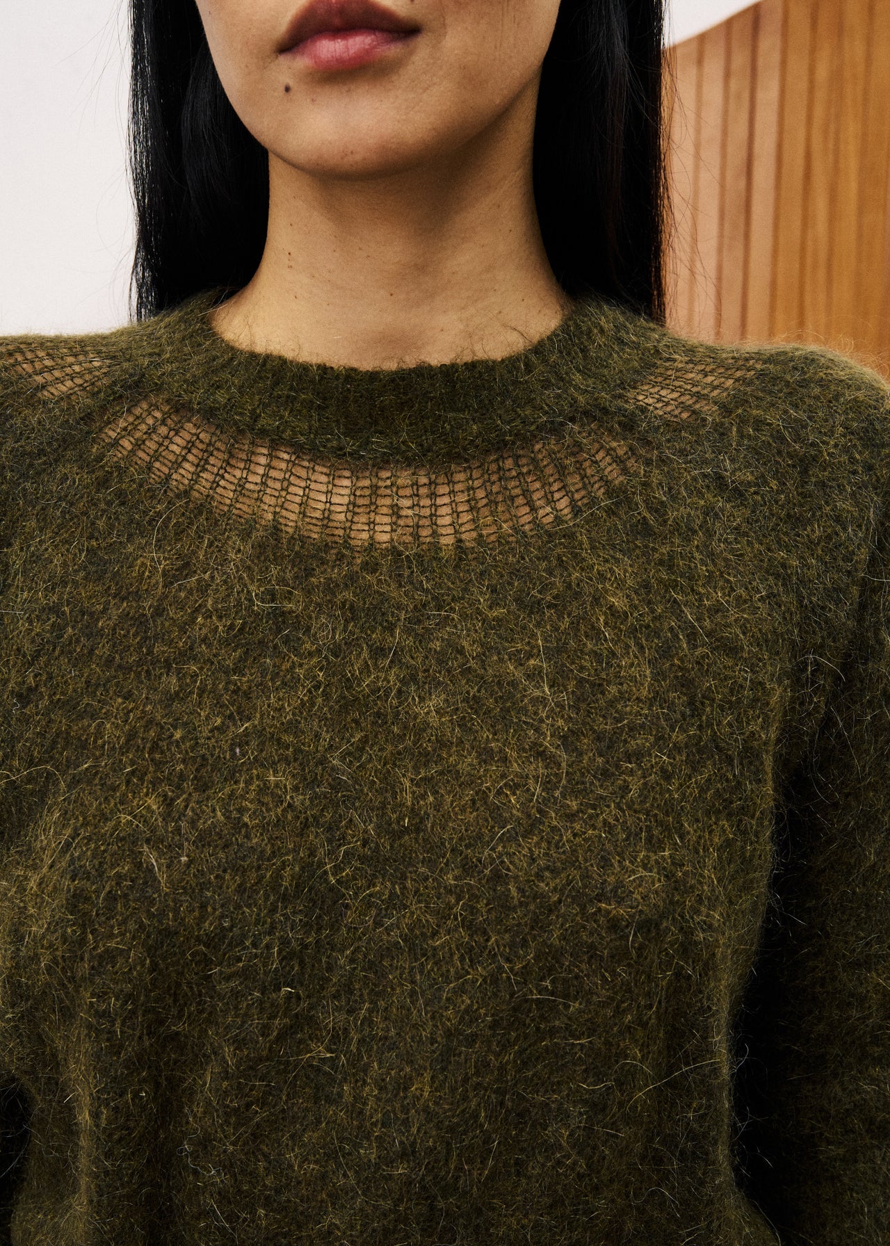Person wearing a textured green sweater with a blurred background