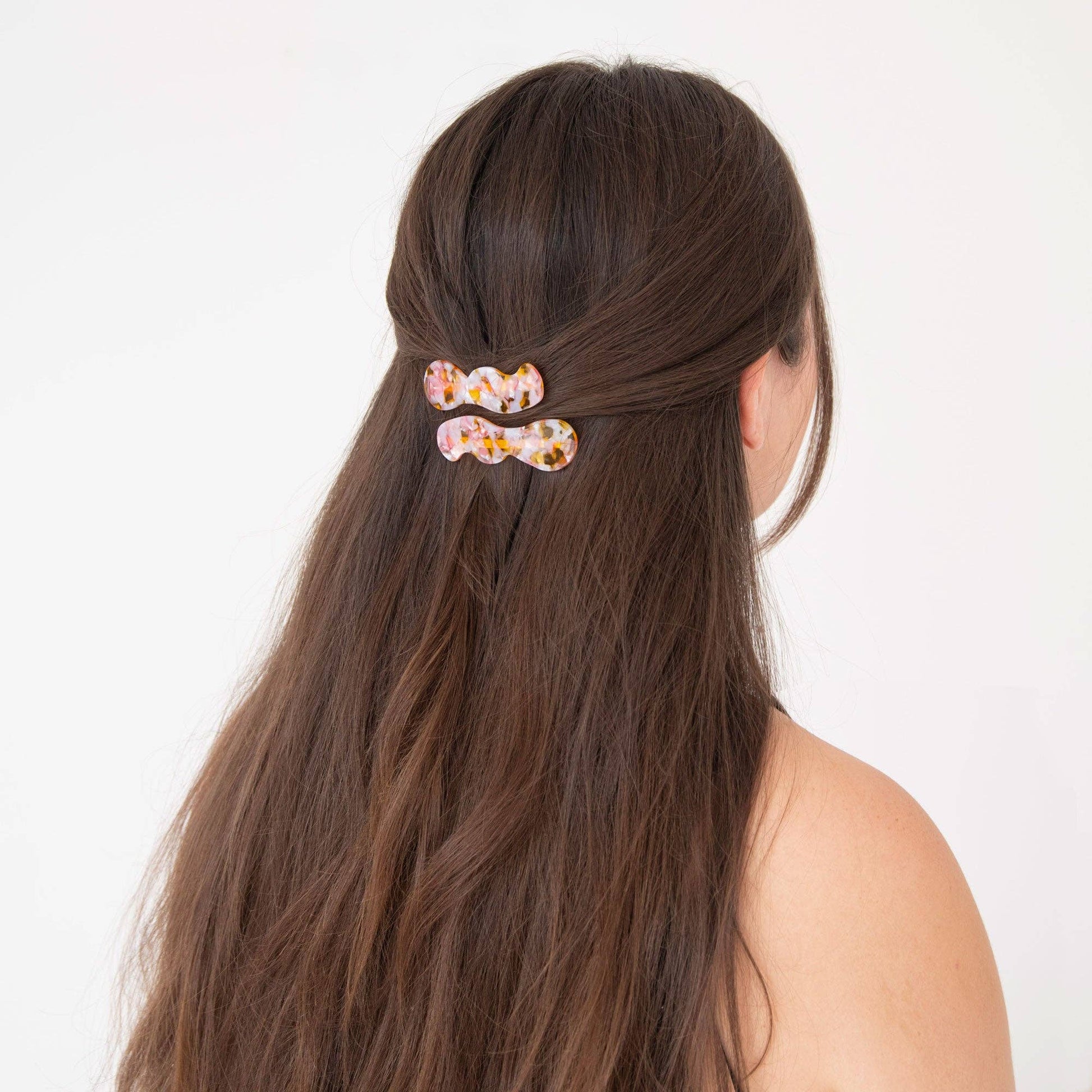 Hair clip with floral design in a person's hair on a white background