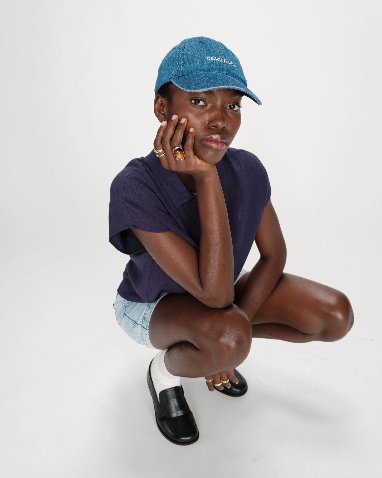 Person wearing a navy blue cap and t-shirt, sitting on a white background