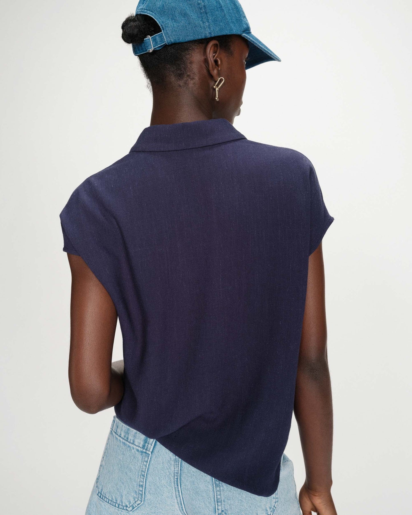 Person wearing a navy blue polo shirt and light blue jeans with a white background
