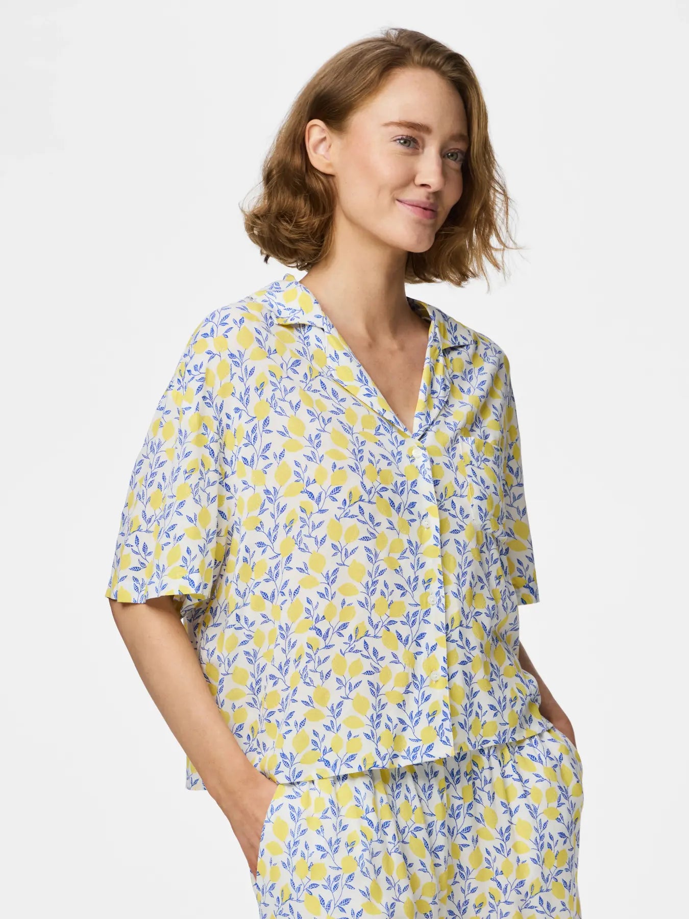 Woman wearing a yellow and blue floral pajama set on a white background