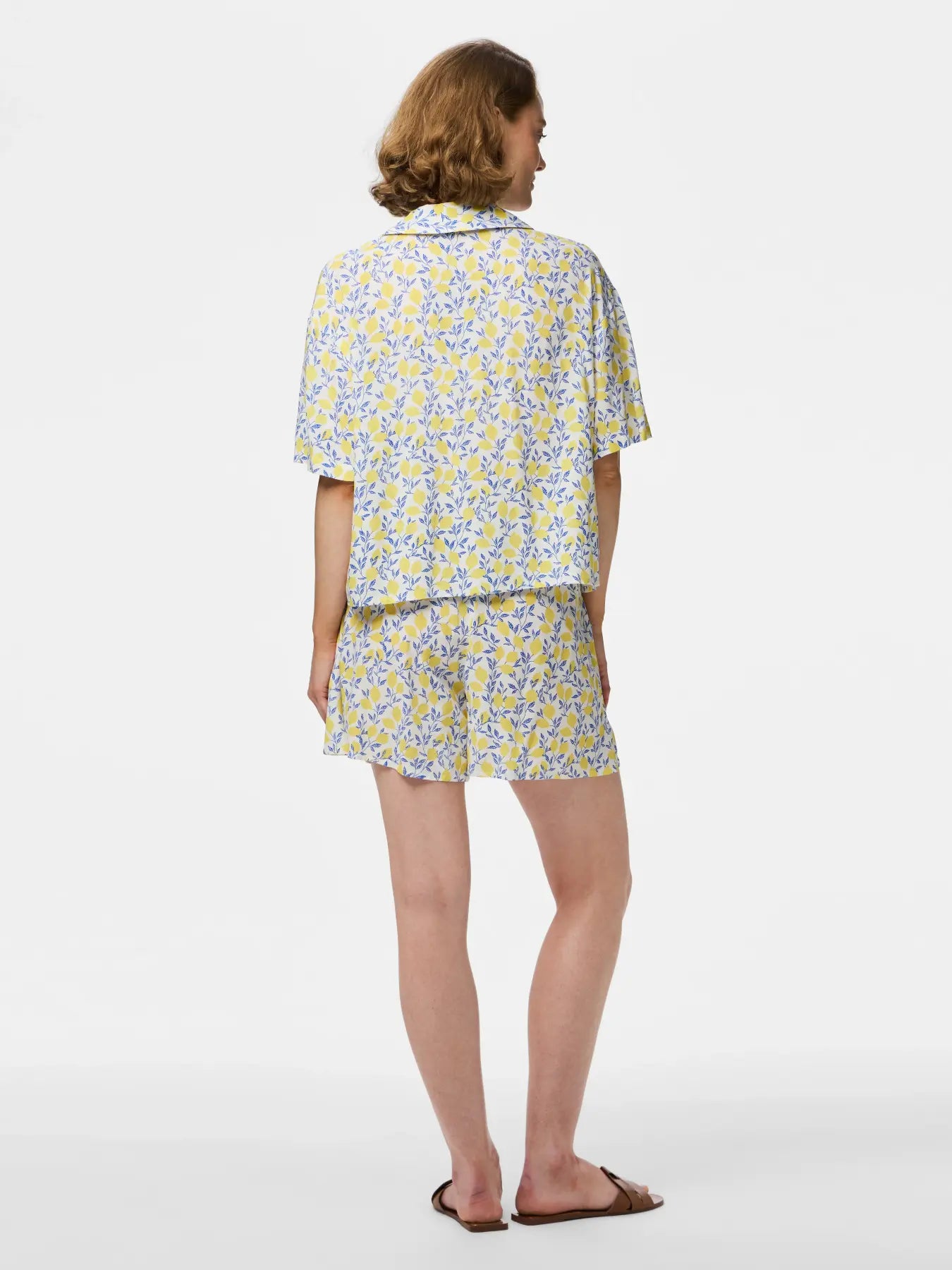 Woman wearing a floral shirt and shorts set on a white background