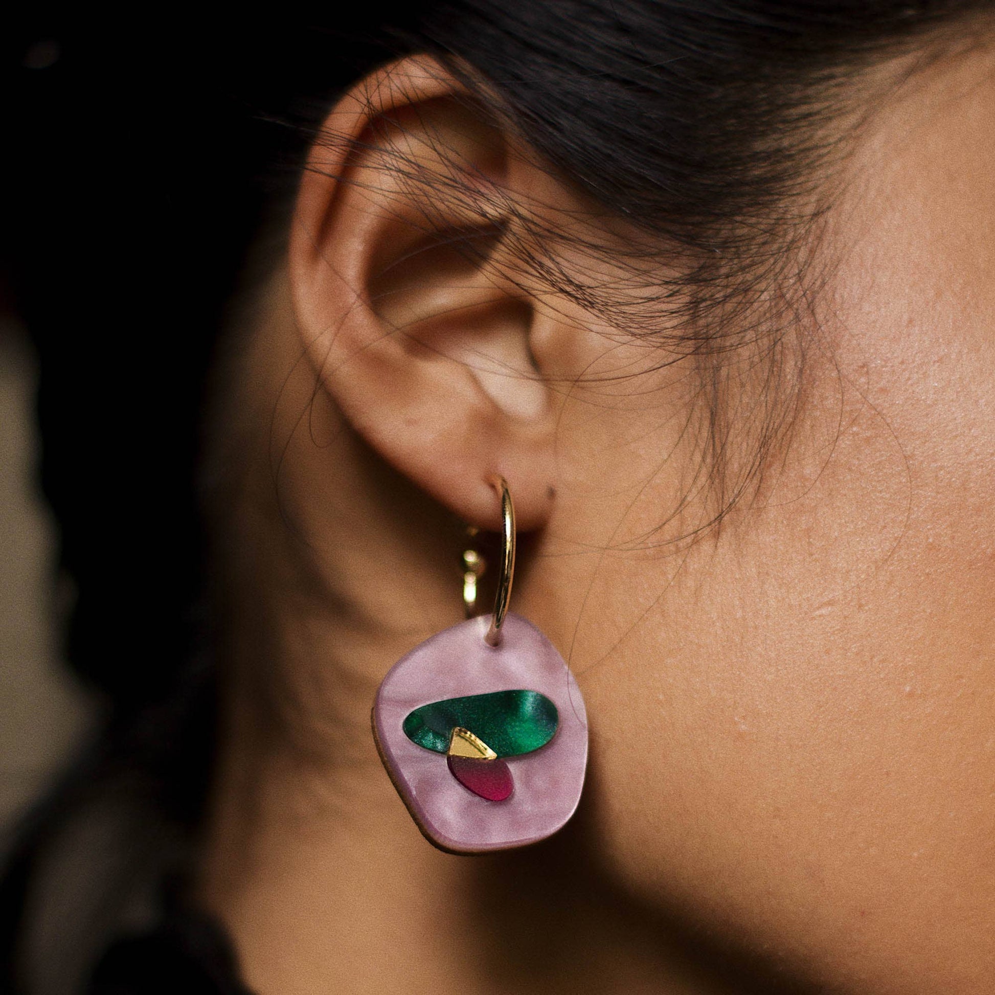 Close-up of an ear wearing a colorful earring with a blurred background