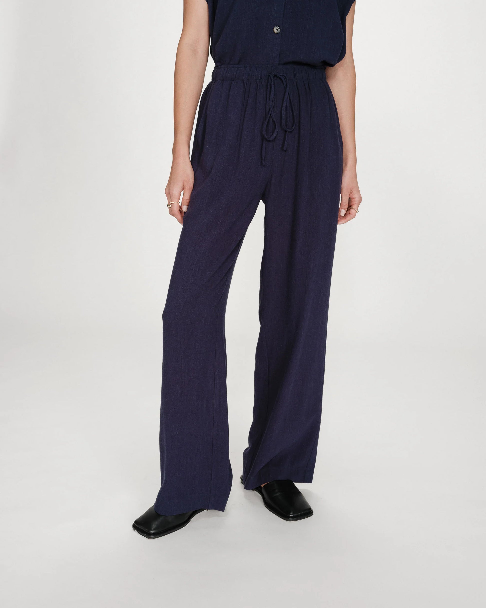 Person wearing a navy blue jumpsuit on a white background