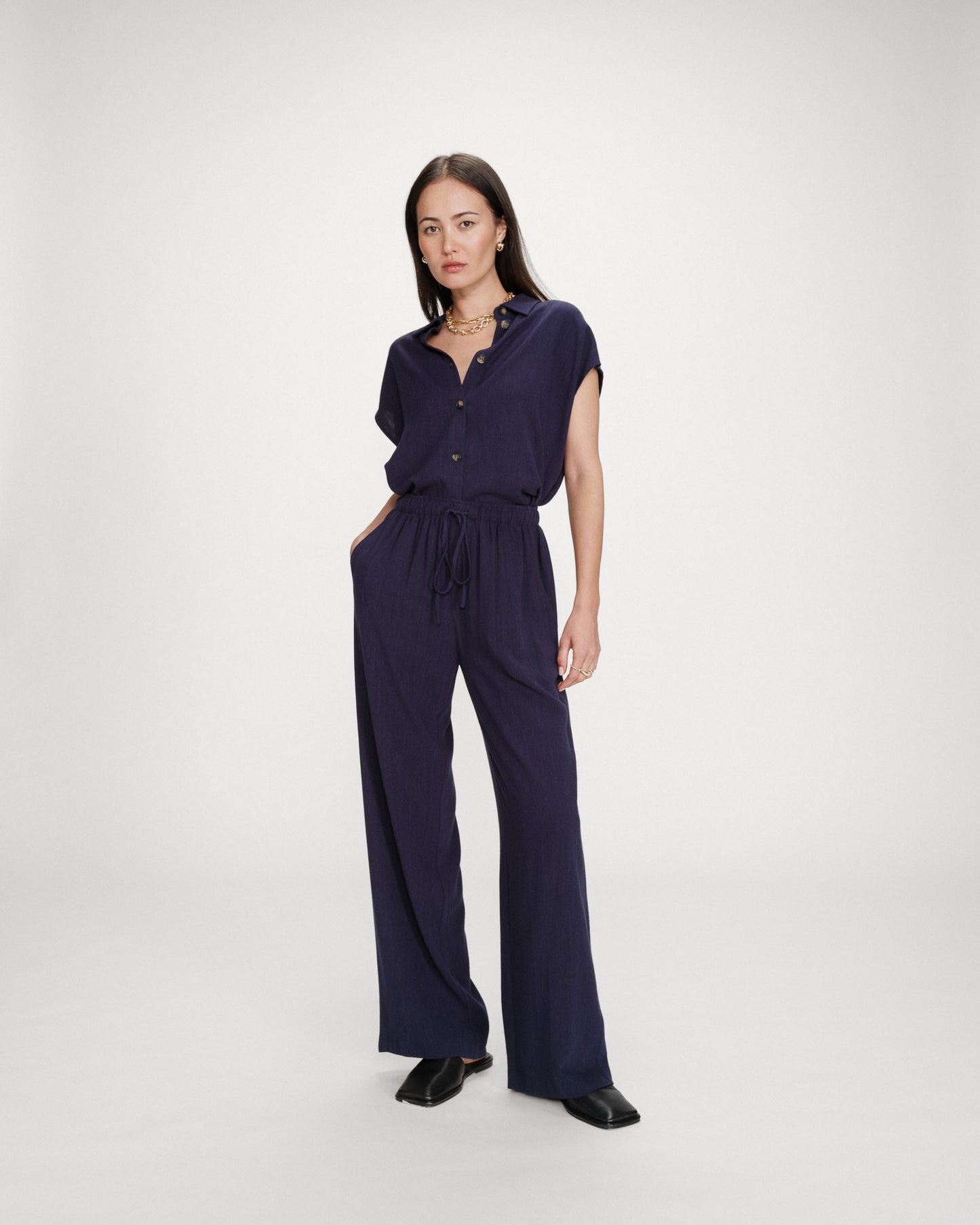 Woman wearing a navy blue jumpsuit on a white background