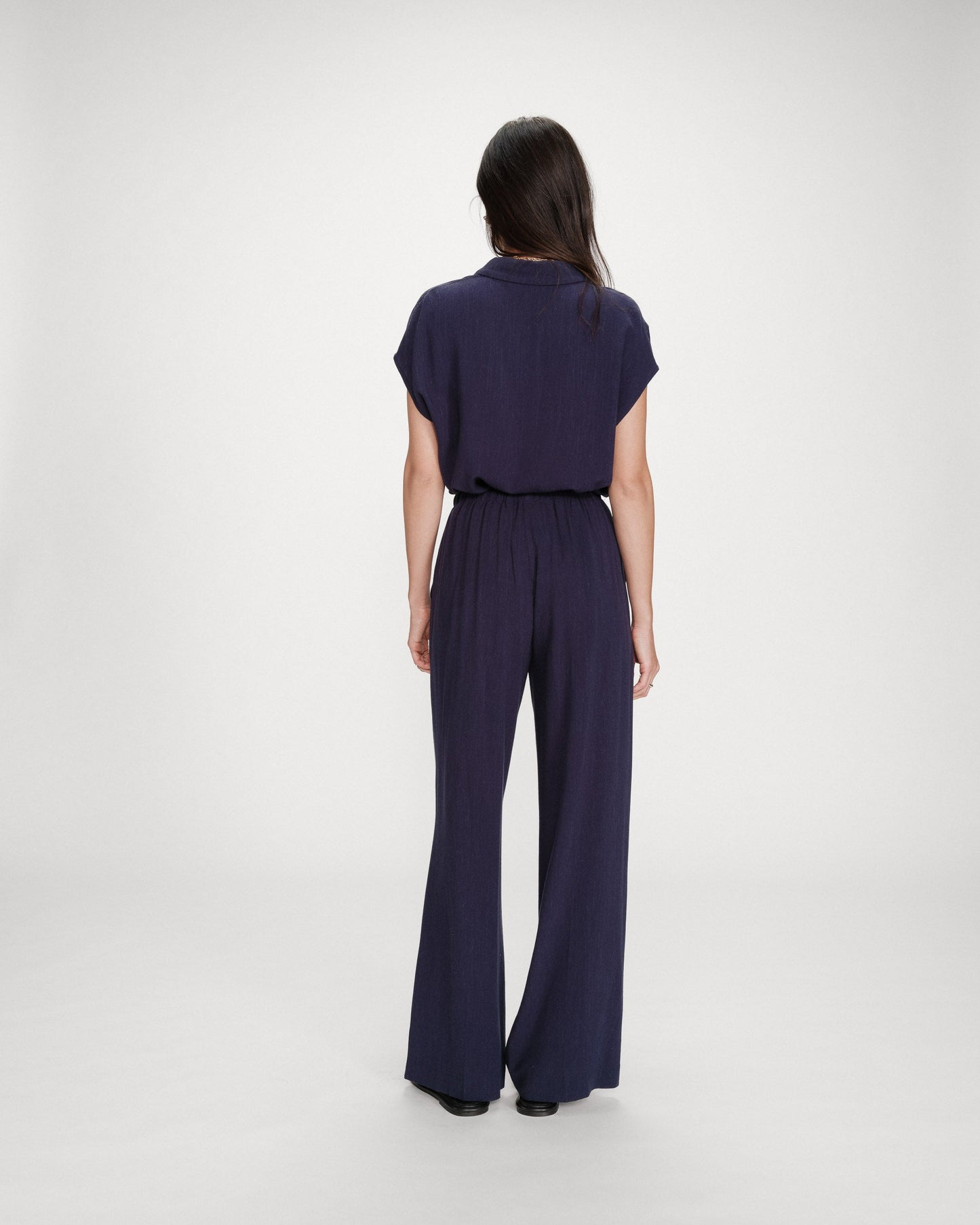 Person wearing a navy jumpsuit on a white background