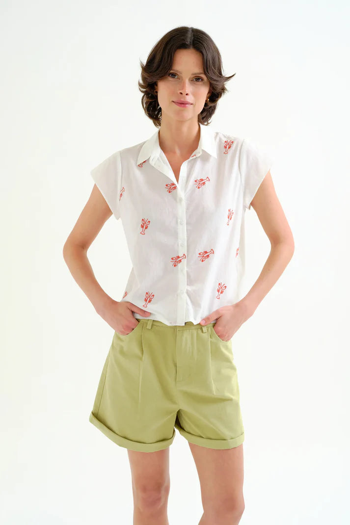 Person wearing a white shirt and light green shorts on a plain background