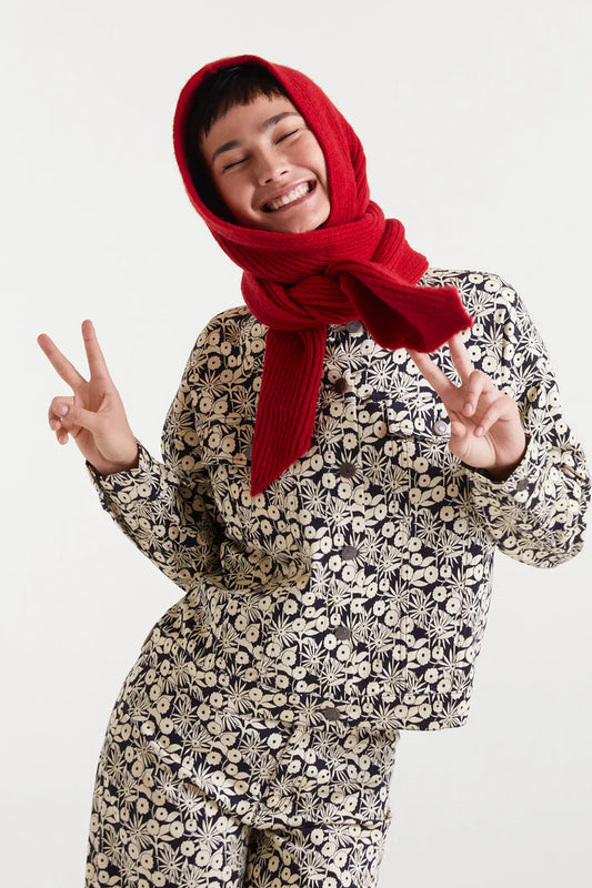 Person wearing a red headscarf and floral outfit making peace signs against a white background