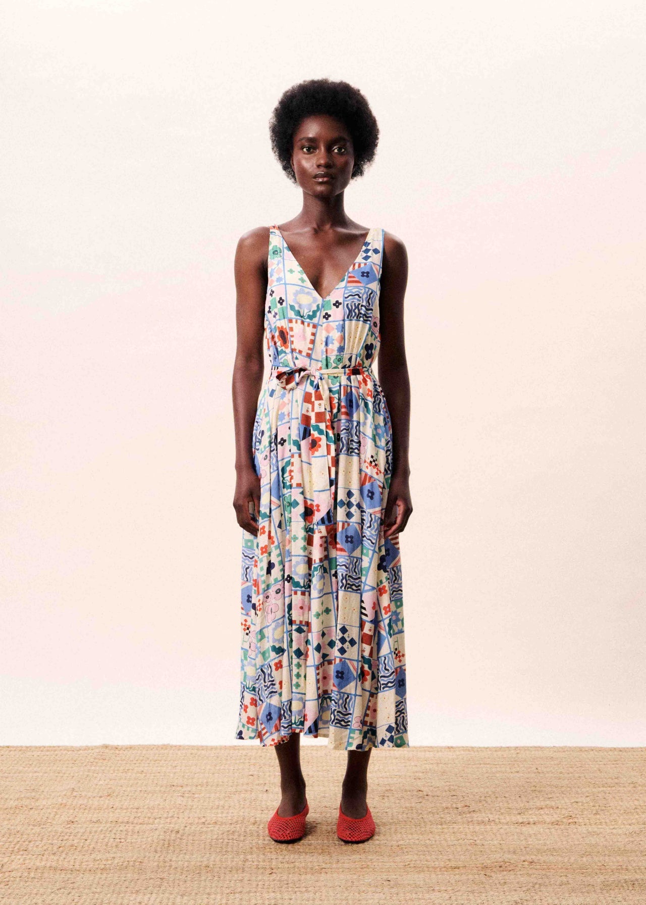 Woman wearing a colorful floral dress against a plain background