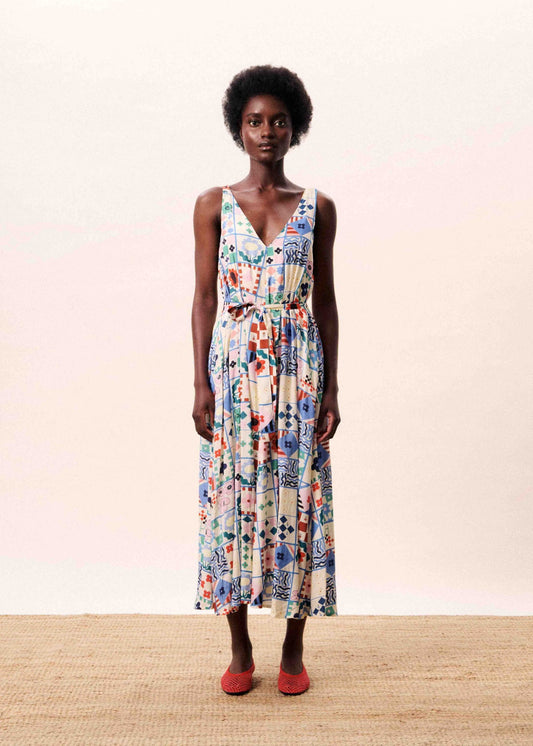 Woman wearing a colorful floral dress against a plain background