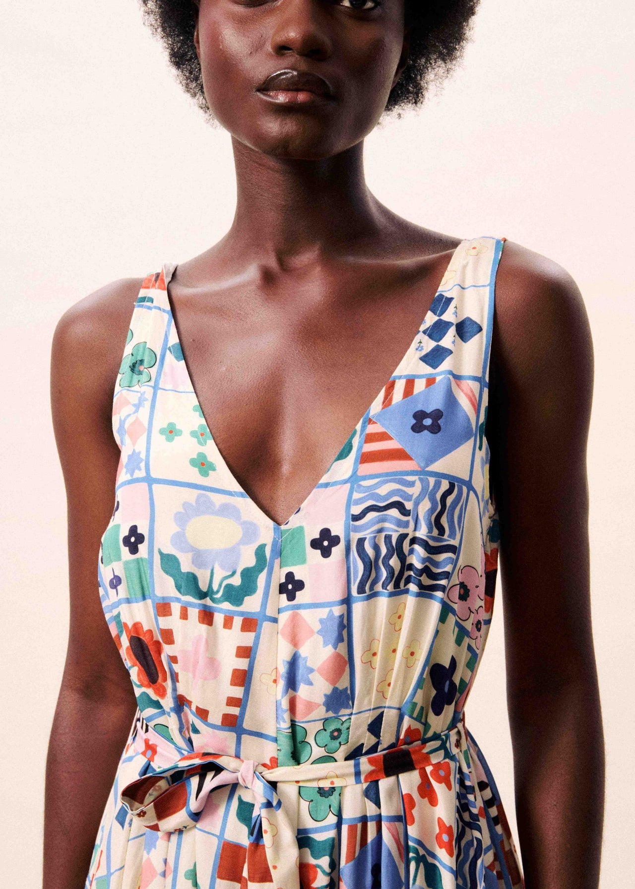 Woman wearing a colorful patterned dress against a plain background