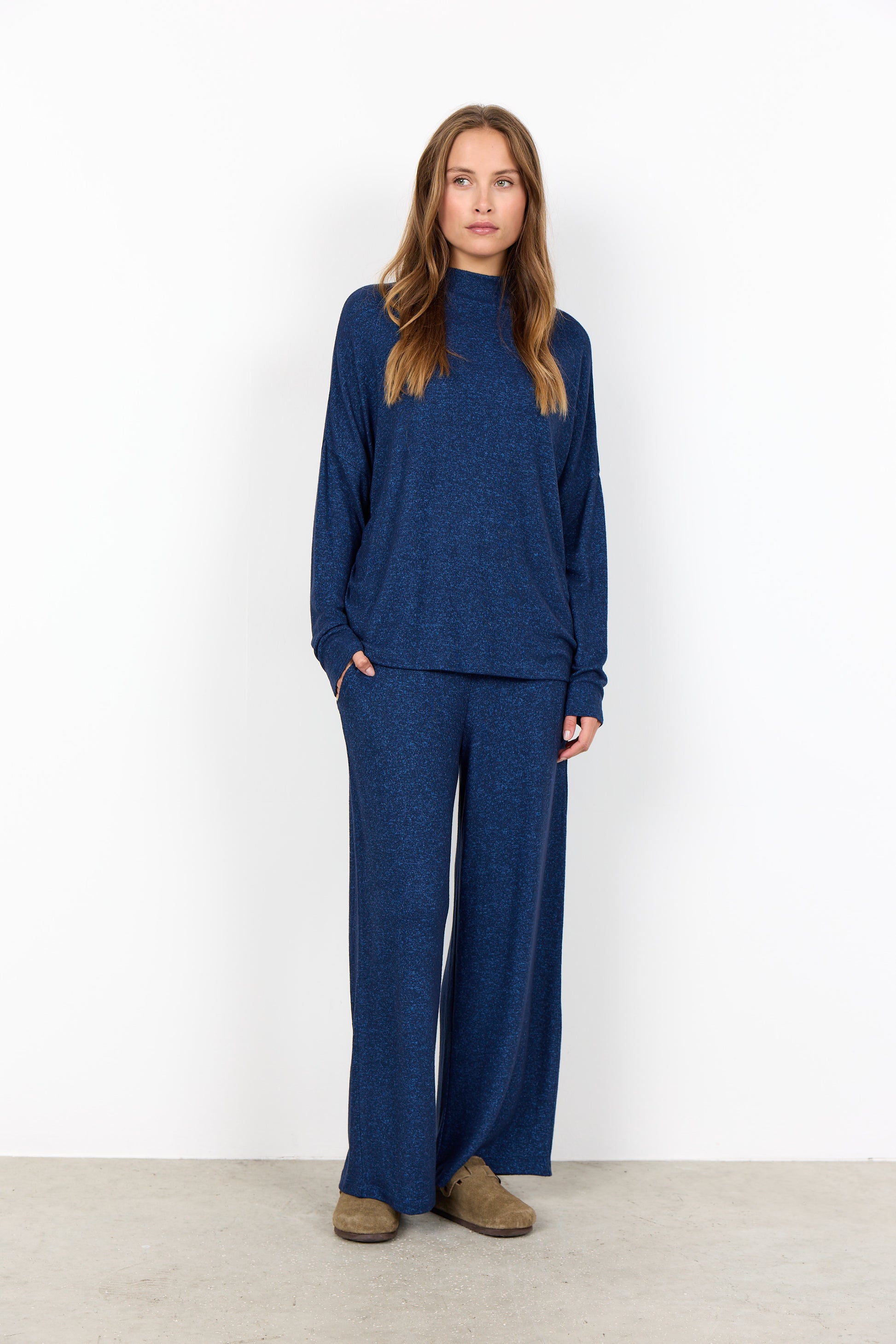 Woman wearing a blue outfit standing against a white background