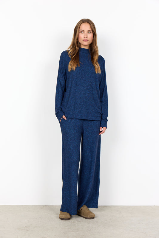 Woman wearing a blue outfit standing against a white background