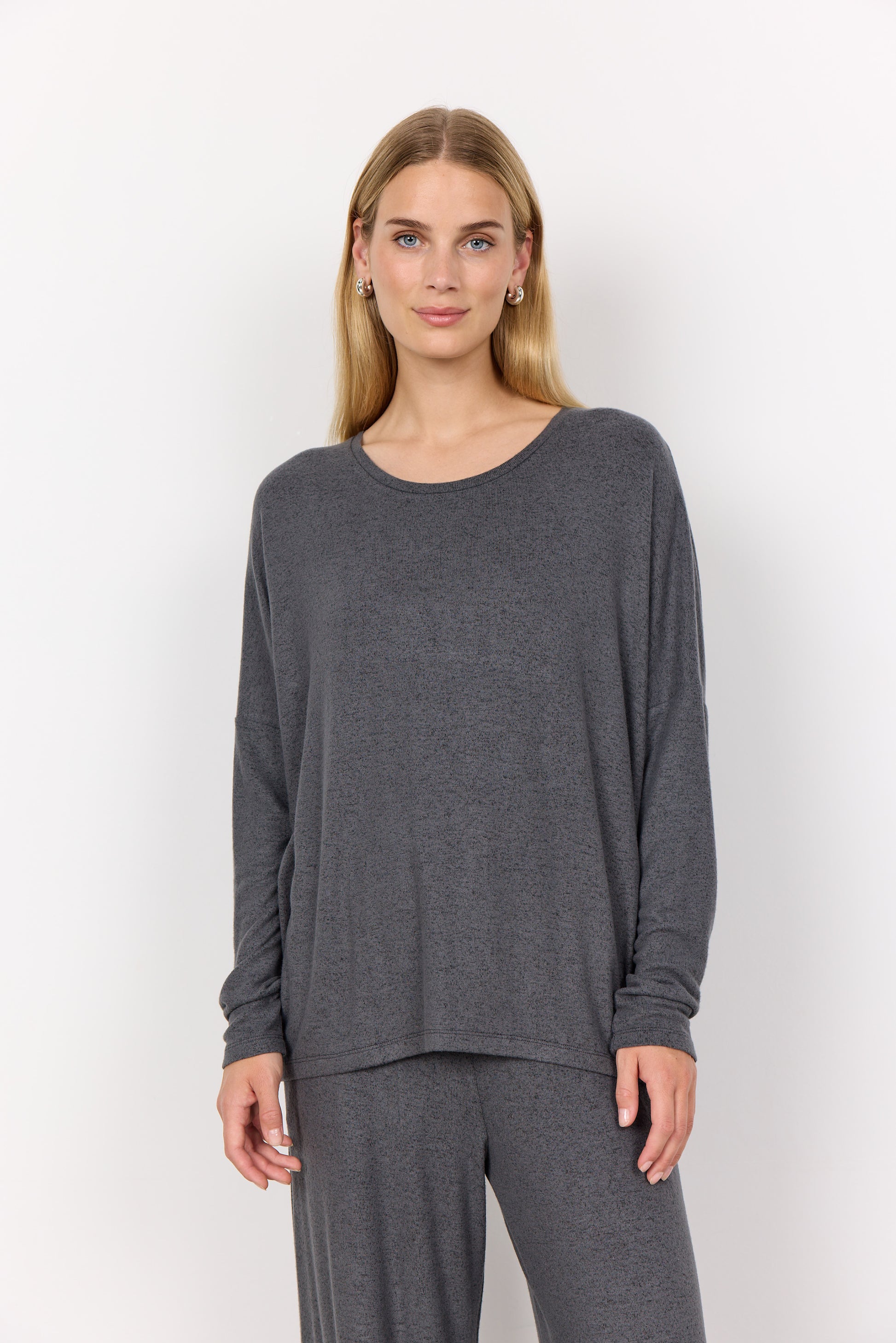 Woman wearing a grey long-sleeve top and pants on a white background