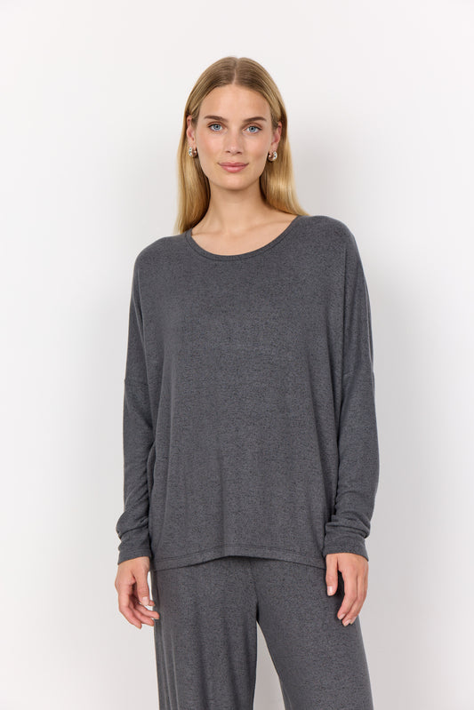 Woman wearing a grey long-sleeve top and pants on a white background