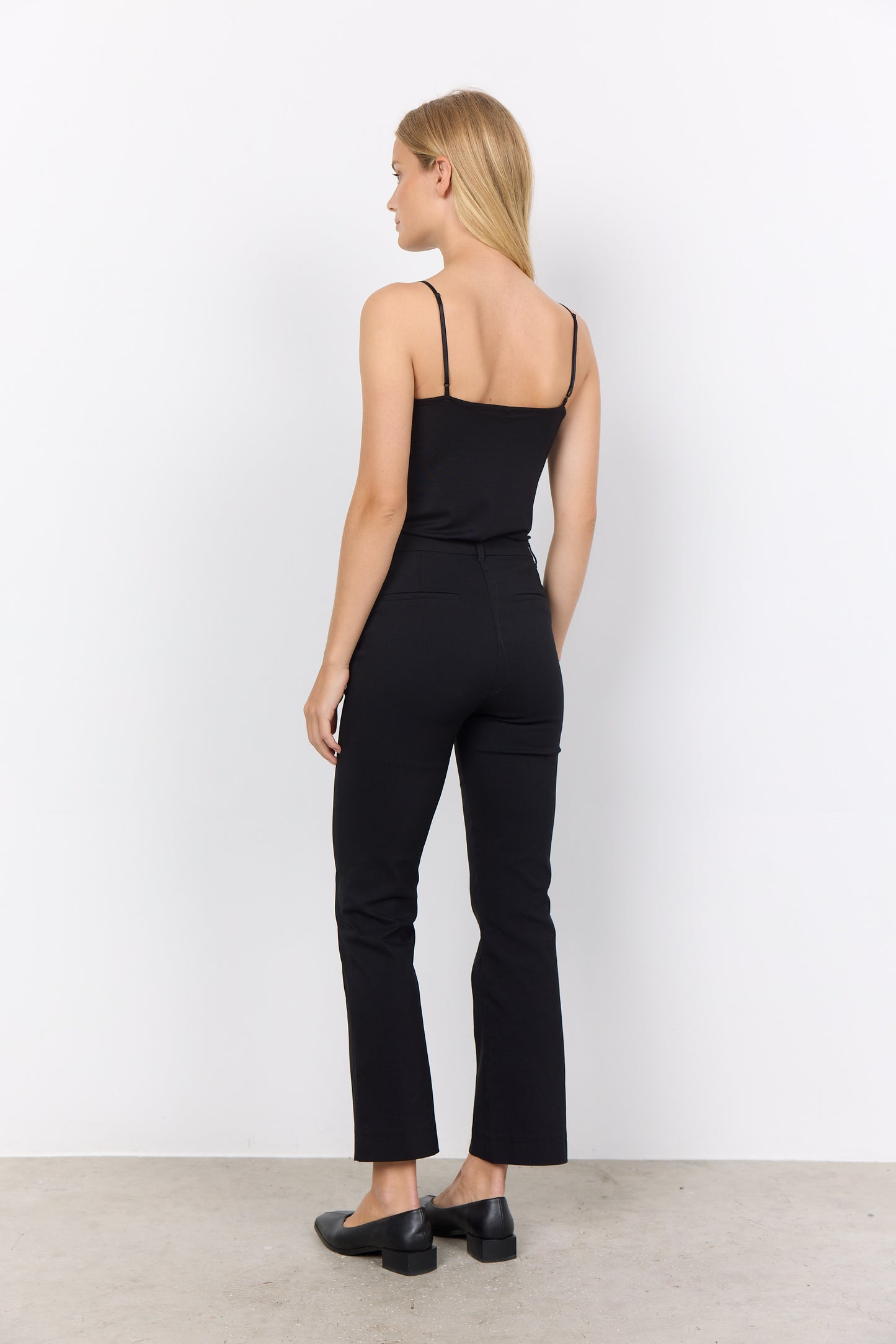 Woman wearing a black jumpsuit against a white background