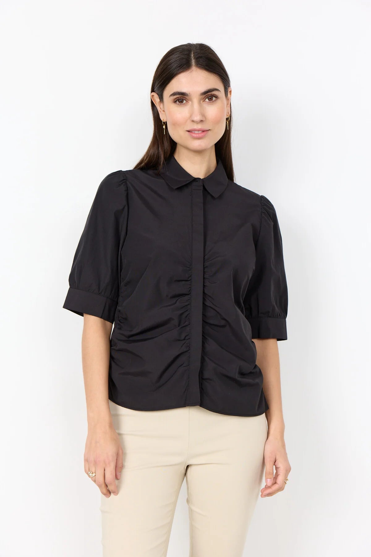 woman wearing a black shirt and cream pants on a white background