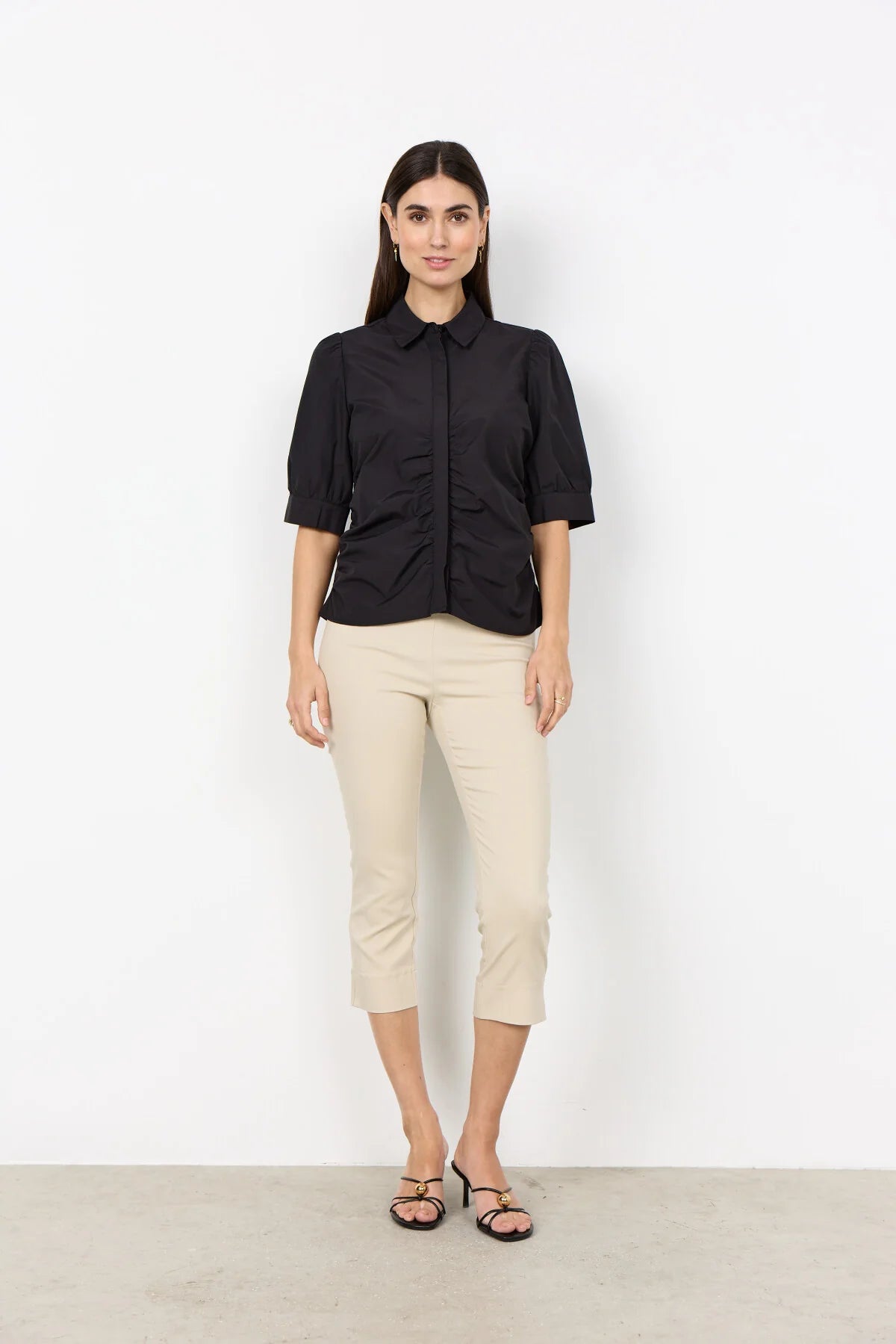 woman wearing a black shirt and cream pants on a white background