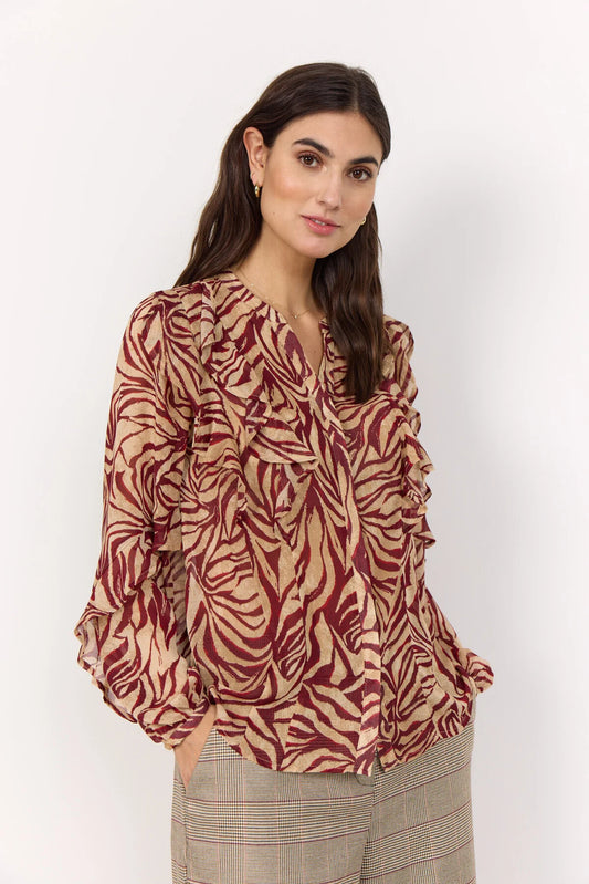 Woman wearing a patterned blouse with long sleeves on a white background